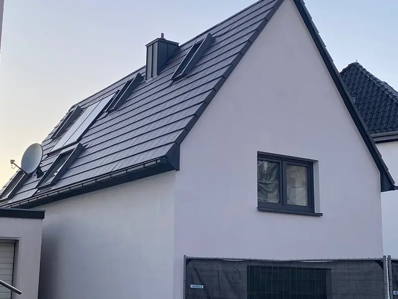 Weißes Giebelhaus mit neu eingedecktem dunklem Dach